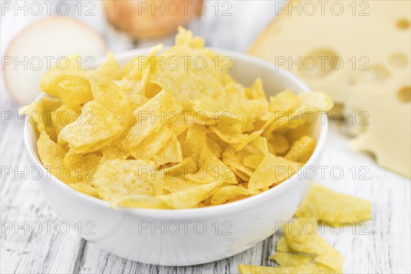 Cheese and Onion Potato Chips on an old wooden table as detailed close-up shot (selective focus)