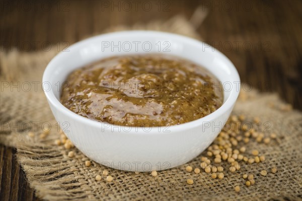 Mustard (sweet) on rustic wooden background (close-up shot)