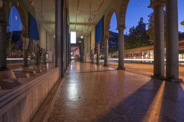 Shopping Street with Shops and Reflection Below Archway in Dusk and Long Exposure in City of Locarno, Ticino, Switzerland, Europe