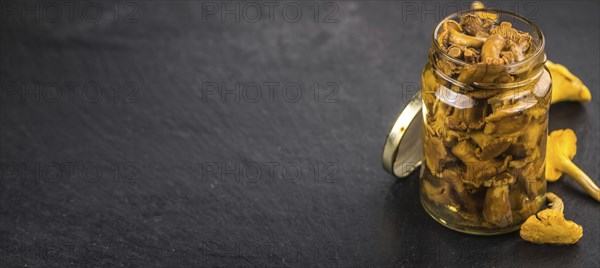 Portion of Preserved chanterelles on a rustic slate slab, selective focus, close-up shot