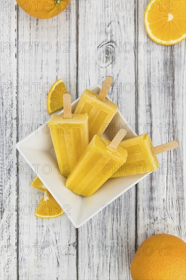 Orange Popsicles (selective focus, close-up shot) on a vintage background