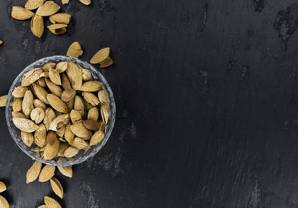 Roasted and salted Almonds (with shell) on a vintage background (close-up shot)
