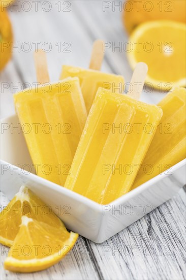 Some homemade orange popsicles on a vintage background (selective focus, close-up shot)
