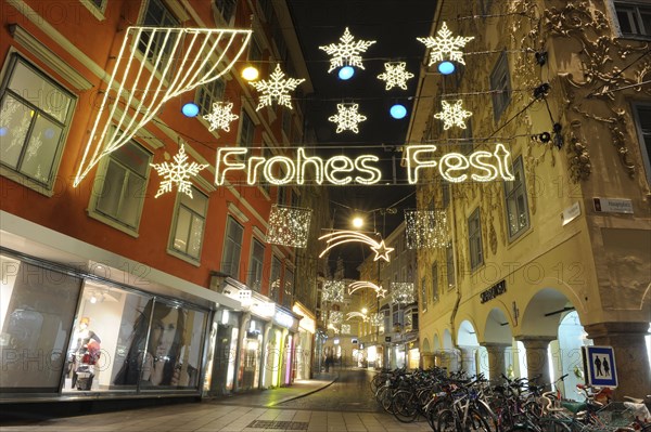 A Christmas-lit alleyway with the inscription 'Merry Christmas', snowflakes and lots of bicycles on a winter evening, Sporgasse, Graz