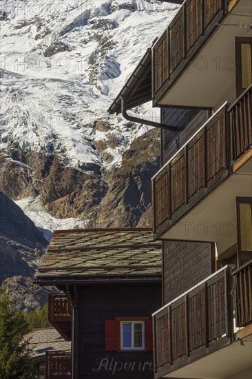 Wooden balconies in a mountain village, with snow-capped mountains in the background, Saas Fee, Switzerland, Europe