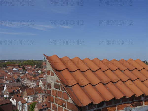 Red tiled roof and brick structure overlooking a historic old town and clear skies, lüneburg, germany