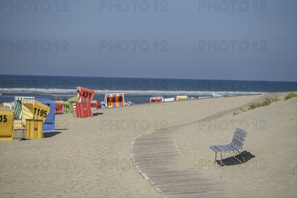 Colourful beach chairs on a sandy beach with a wooden path, quiet atmosphere, langeoog, germany