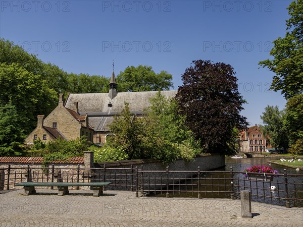 Picturesque parkland with historic buildings, a canal and bridge, surrounded by trees and flowers, Bruges, Belgium, Europe