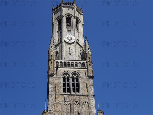 Gothic bell tower with clock in front of a slow sky, Bruges, Belgium, Europe