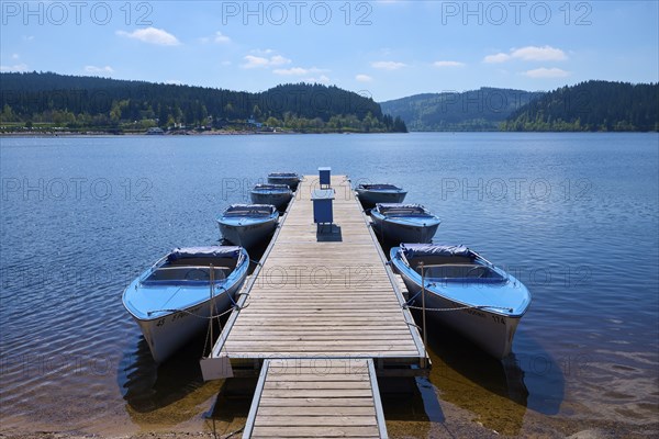 Jetty with moored boats on the Schluchsee, surrounded by mountains and forests, under blue sky, spring, Schluchsee, Black Forest, Baden-Württemberg, Germany, Europe