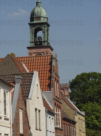 Traditional houses and a church tower with red tiled roofs under a clear sky, friedrichstadt, schleswig-holstein, germany