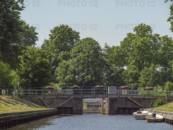 A bridge over a canal, surrounded by green trees and boats on the bank, summer atmosphere, friedrichstadt, schleswig-holstein, germany