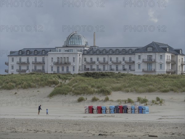 Large hotel with dome in the background, in front of it sandy beach with some people, cloudy sky, juist, east frisia, Germany, Europe
