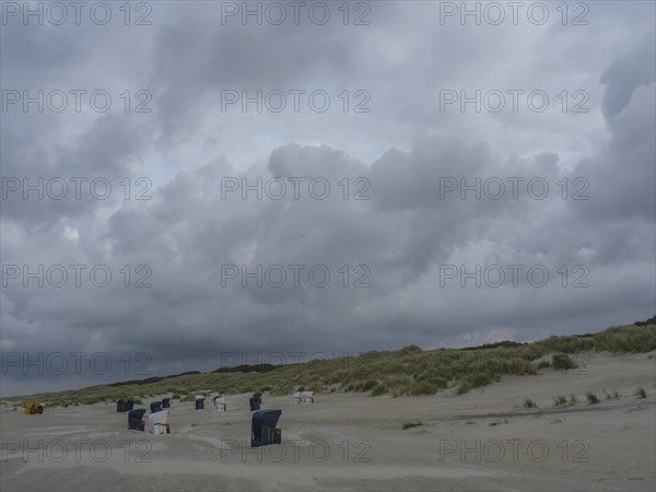 Empty beach with beach chairs, large dunes and dark grey clouds in the sky, juist, east frisia, Germany, Europe