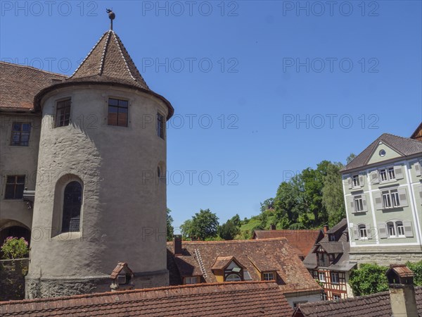 A castle with a round tower and surrounding roofs of historic buildings under a clear blue sky, Meersburg, Germany, Europe