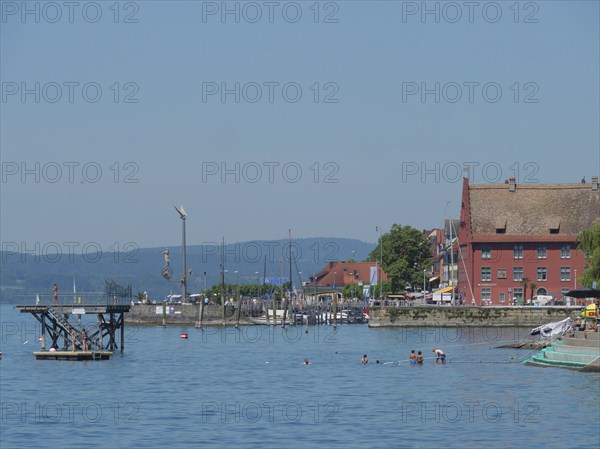 Harbour view with boats and classic buildings on the shore of a lake under a clear summer sky, Meersburg, Germany, Europe