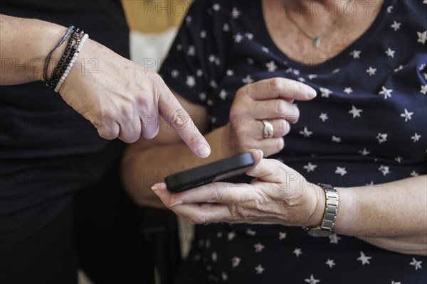 A daughter explains how to use a smartphone to her mum. Berlin, 05.08.2024