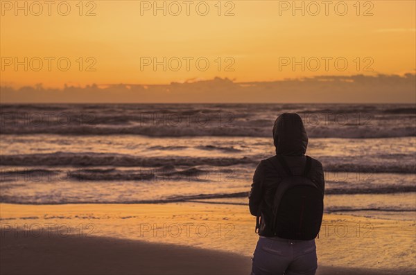 Woman looking at the horizon, beach at sunset