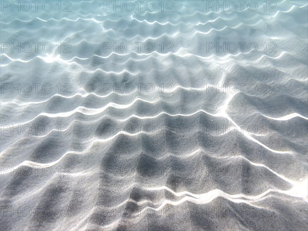 Wave patterns and light reflections in the clear water over a sandy bottom. Calm and peaceful atmosphere