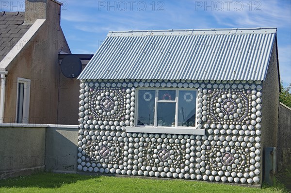 House facade decorated with shells, including a window, next to another building and garden, Mainand, Shetland Islands, Scotland, United Kingdom, Europe