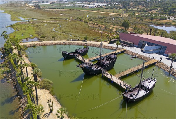 Historically modelled sailing ships in a calm water basin, surrounded by landscape under a clear sky, aerial view, Muelle de las Carabelas, reproductions of La Nina, La Pinta and La Santa Maria, Museum, Palos de la Frontera, Province of Huelva, Andalusia, Spain, Europe