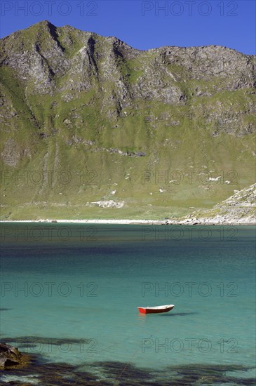 A red boat floats in a turquoise-coloured lake in front of a mountainous landscape, Haukland, Leknes, Lofoten, Nordland, Norway, Europe