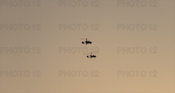 Two gyrocopters flying at sunrise, silhouettes against the morning sky, Mpumalanga, South Africa, Africa
