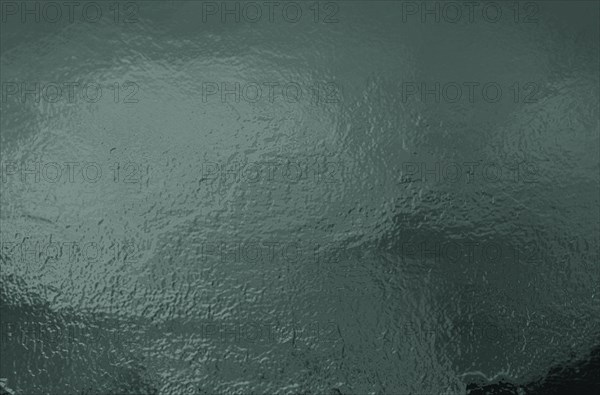 Abstract green textured image with a reflective, glossy and wavy surface resembling water