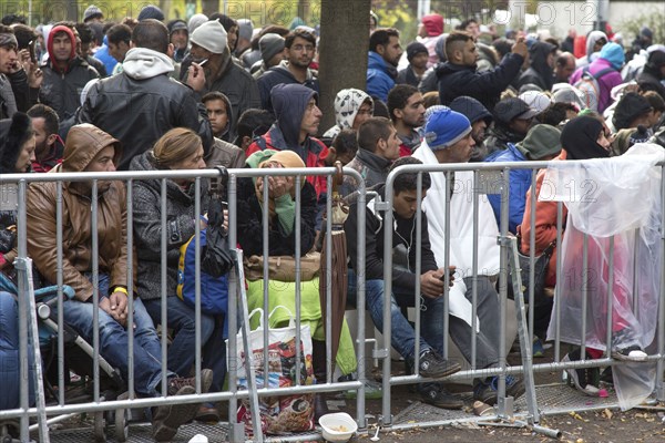 Refugees from Syria wait behind barriers in the Central Reception Centre for Asylum Seekers at the Berlin State Office for Health and Social Affairs for their registration, 09.10.2015