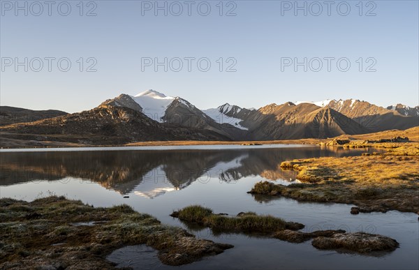 Glaciated mountain peaks reflected in a mountain lake at sunset, Arabel Lake at Arabel Pass, Issyk Kul Province, Kyrgyzstan, Asia