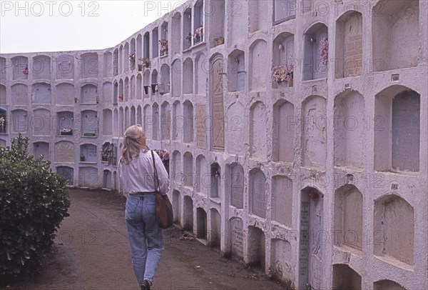 Woman visits burial site in Calella, Costa Brava, Barselona, ​​Catalonia, Spain, Southern Europe. Scanned thumbnail slide, vintage, retro, funny, Europe