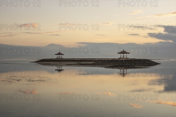 Beautiful seascape in the morning. Tropical sandy beach with breakwater and reflection of the sky in the calm water. Morning landscape, taken in Sanur, Bali, Indonesia, Asia
