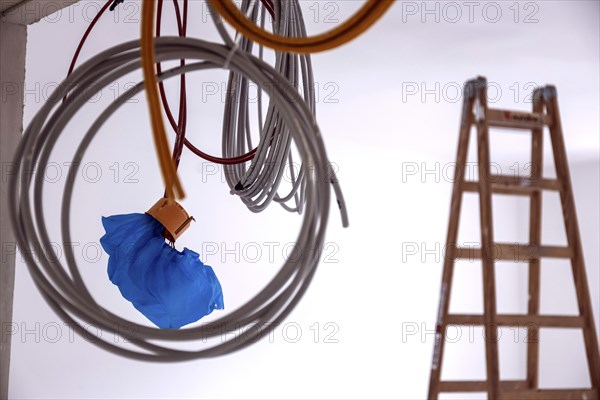 Cables hanging from a construction site on a wall, in the background is a ladder, Berlin, 03.07.2024., Berlin, Berlin, Germany, Europe
