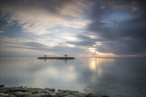 Beautiful seascape in the morning. Tropical sandy beach with breakwater and reflection of the sky in the calm water. Morning landscape, taken in Sanur, Bali, Indonesia, Asia
