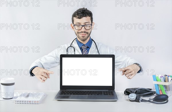 Handsome doctor pointing at an advertisement on the laptop screen. Smiling doctor pointing at an advertisement on the laptop screen