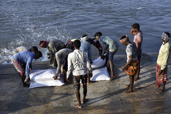 Public Works Department (PWD) of Assam labourer throwing sand bag from boat in the banks of Beki River to reduce soil erosion in Barpeta, Assam in India on Tuesday, November 13, 2018. The soil erosion of Beki river has become a major problem of flowing two districts Barpeta and Baksa of Assam