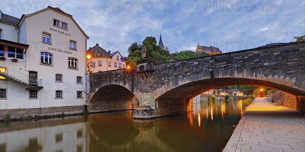 Town view of Vianden with the old stone bridge over the river Our and the castle in the evening, Grand Duchy of Luxembourg