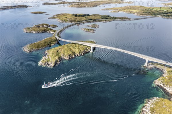 Aerial view of bridge connecting islands at the norwegian coast, fishing boat passing below the bridge, Norway, Europe