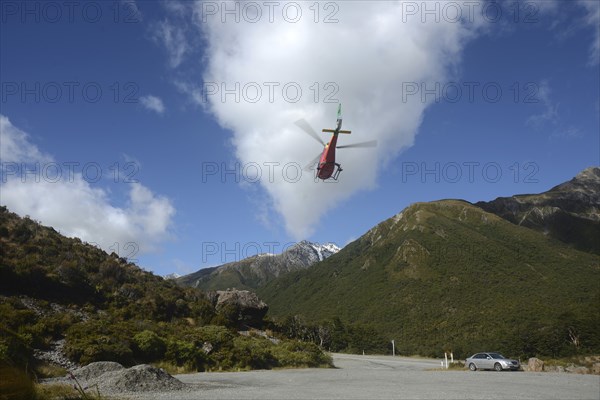 ARTHURS PASS, NEW ZEALAND, 2021-01-29: A brightly painted helicopter takes off from a car park in Arthur's Pass National Park, New Zealand, Oceania