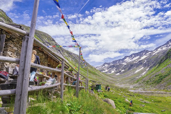Scenery with a mountain farm, colourful flags and a path through the green mountain landscape under a cloudy sky, Klein Tibet, Zillertal, Austria, Europe