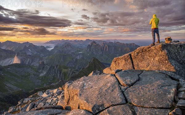 View over mountain top and sea, dramatic sunset, climbers at the top of Hermannsdalstinden, Moskenesöy, Lofoten, Nordland, Norway, Europe