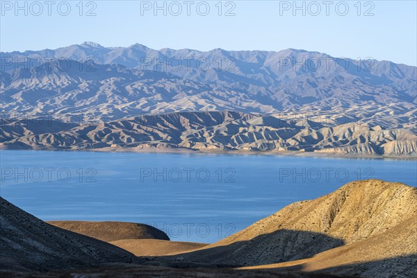 Blue Toktogul reservoir between dry mountain landscape, hilly mountains in the evening light, Jalalabad region, Kyrgyzstan, Asia