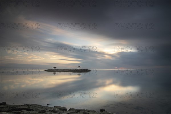 Beautiful seascape in the morning. Tropical sandy beach with breakwater and reflection of the sky in the calm water. Morning landscape, taken in Sanur, Bali, Indonesia, Asia