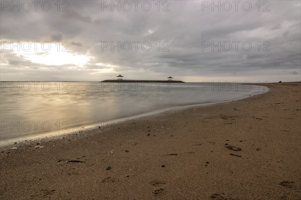 Beautiful seascape in the morning. Tropical sandy beach with breakwater and reflection of the sky in the calm water. Morning landscape, taken in Sanur, Bali, Indonesia, Asia