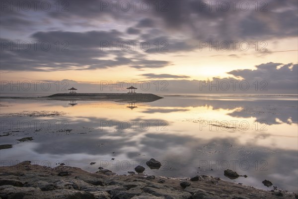 Beautiful seascape in the morning. Tropical sandy beach with breakwater and reflection of the sky in the calm water. Morning landscape, taken in Sanur, Bali, Indonesia, Asia