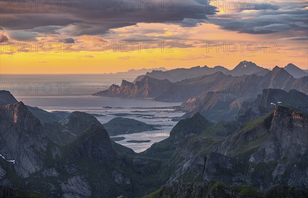 View over mountain top and sea to Fredvang, dramatic sunset, from the top of Hermannsdalstinden, Moskenesöy, Lofoten, Nordland, Norway, Europe