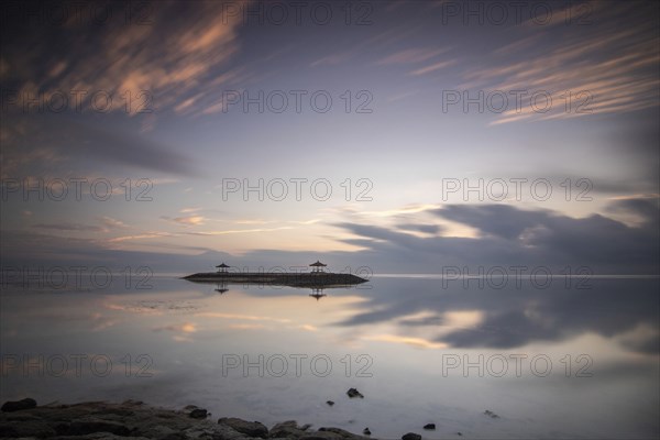 Beautiful seascape in the morning. Tropical sandy beach with breakwater and reflection of the sky in the calm water. Morning landscape, taken in Sanur, Bali, Indonesia, Asia