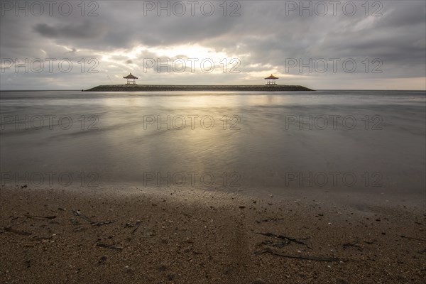 Beautiful seascape in the morning. Tropical sandy beach with breakwater and reflection of the sky in the calm water. Morning landscape, taken in Sanur, Bali, Indonesia, Asia