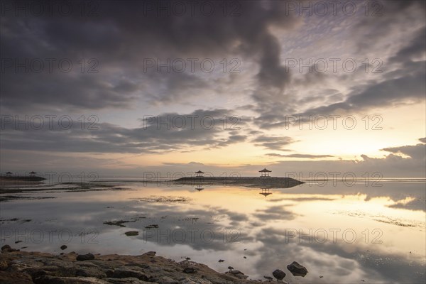 Beautiful seascape in the morning. Tropical sandy beach with breakwater and reflection of the sky in the calm water. Morning landscape, taken in Sanur, Bali, Indonesia, Asia