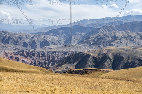 Electric pylon, eroded mountainous landscape with brown hills, mountains and steppe, Chuy province, Kyrgyzstan, Asia